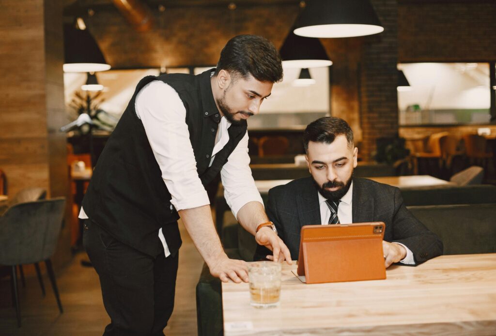 Man in business suit working on iPad being assisted by hotel staff