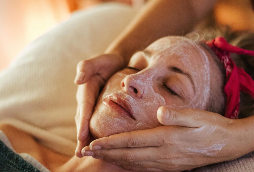 Young woman relaxing and getting a facial massage.